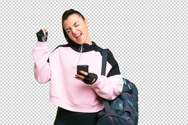 Young sport woman with sport bag over isolated chroma key background with phone in victory position