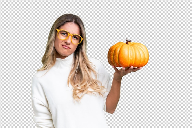 PSD young uruguayan woman holding a pumpkin over isolated background with sad expression