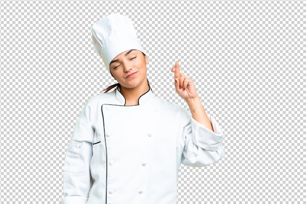 young woman chef over isolated chroma key background with fingers crossing and wishing the best