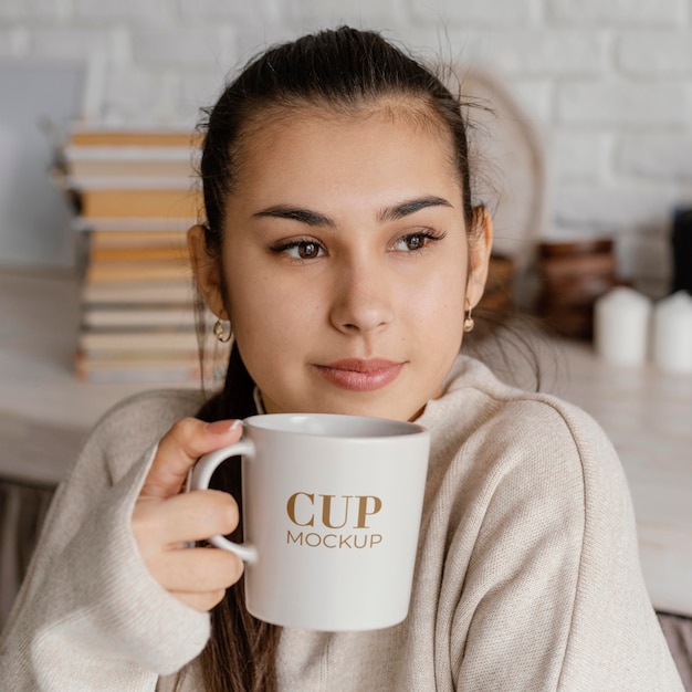 PSD young woman holding a mock-up cup