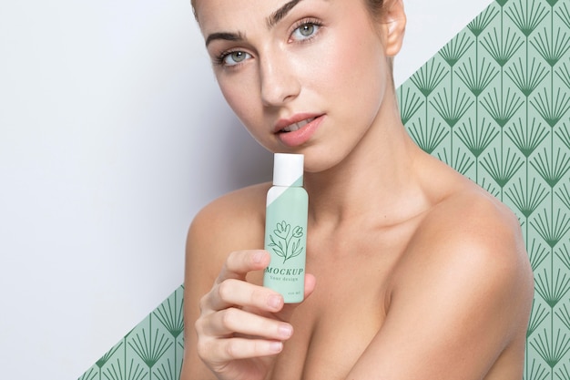 PSD young woman holding a skincare product mock-up