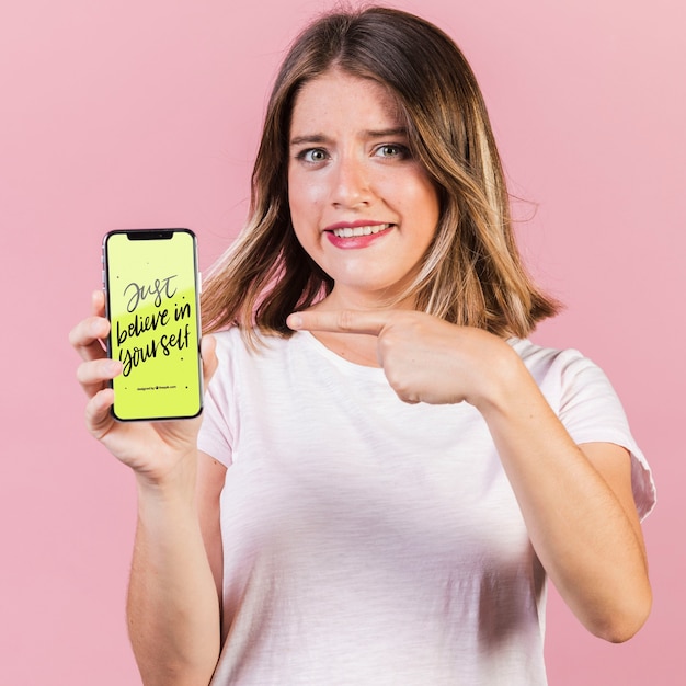 PSD young woman pointing finger at a cellphone mock-up