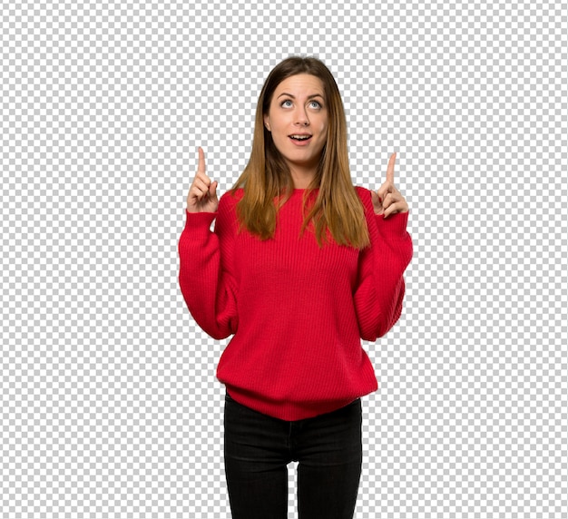 Young woman with red sweater surprised and pointing up