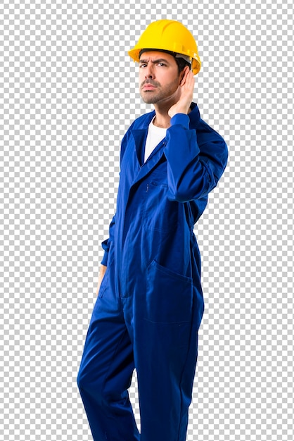 PSD young workman with helmet listening to something by putting hand on the ear