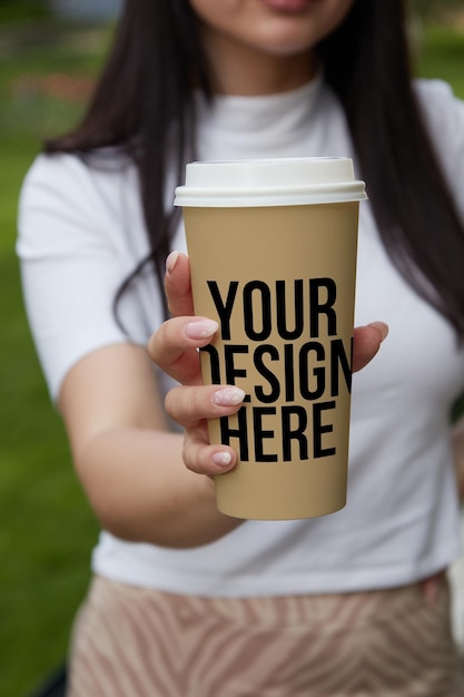 Zandkleur een grote koffiekop in de hand van het meisje veranderlijke kleur mockup psd