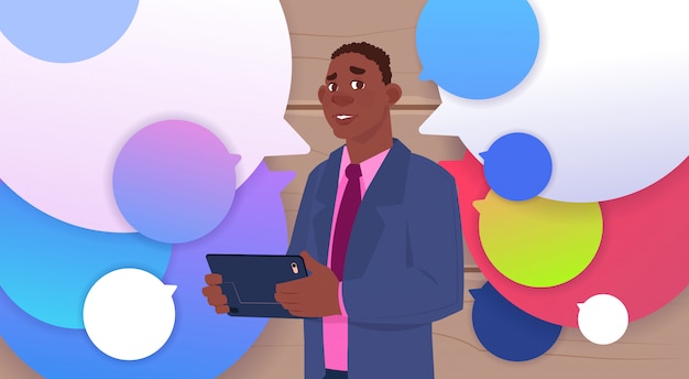 African American Businessman Holding Tablet Speak Over Colorful Chat Bubbles