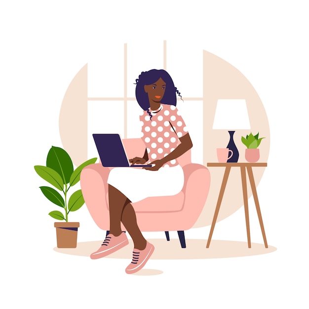 african woman sitting on the armchair with laptop. working on a computer.