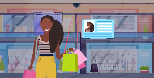 Afro-amerikaanse vrouw met boodschappentassen gezichtsherkenning concept beveiliging camerabewaking cctv-systeem moderne retail mall supermarkt interieur horizontaal portret