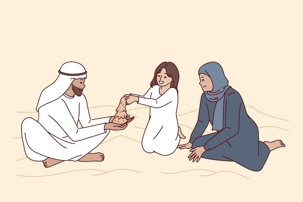 La famiglia araba siede nel deserto con le dune giocando con la figlia con la sabbia e godendosi il fine settimana in comune famiglia felice degli emirati arabi o del qatar vestita con abiti etnici per la cultura orientale concettuale