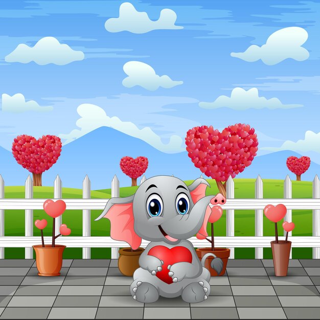 A baby elephant holding red heart in the park landscape