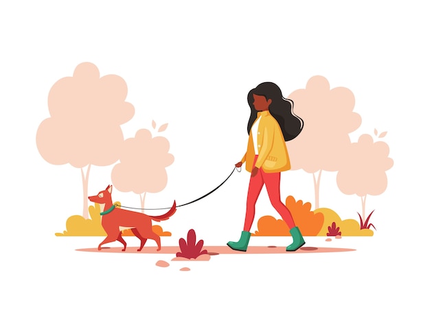 Black woman walking with dog in the park in autumn. outdoor activity concept.