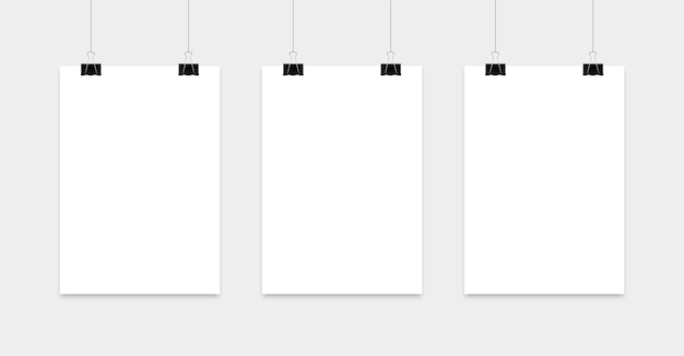 Пустой плакат висит на зажимах. бумажная страница формата а4 в портретном формате. реалистичный лист белой бумаги.