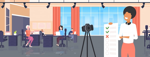 Blogger presentando checklist sondaggio forma esame donna registrazione video online con fotocamera su treppiede valutazione dei risultati concetto di blogging moderno ufficio interno ritratto orizzontale