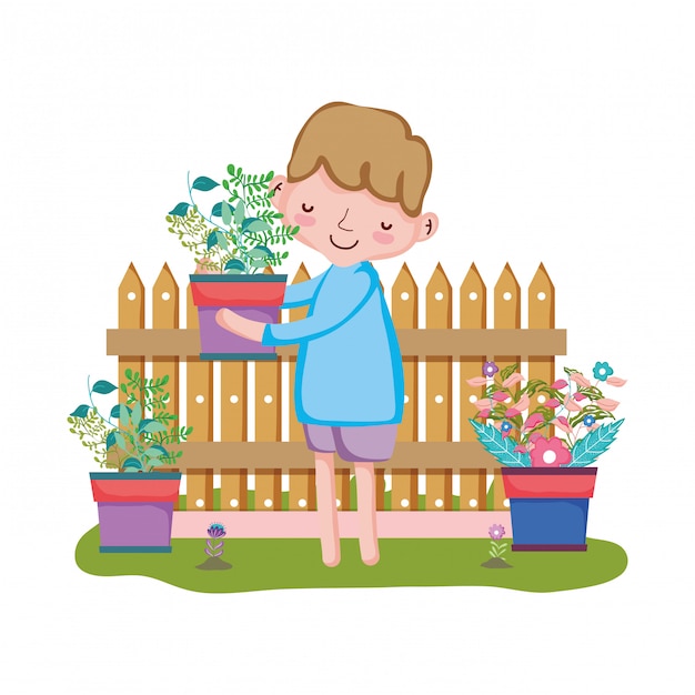 Boy lifting houseplant with fence in the garden