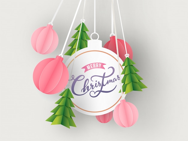 Calligraphy text merry christmas in bauble shape frame with hanging paper cut xmas tree and ornament balls decorated on white background.