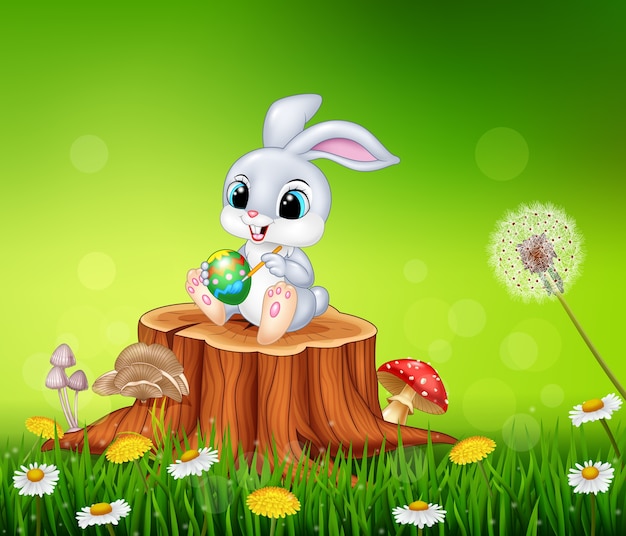 Cartoon easter bunny dipingere un uovo