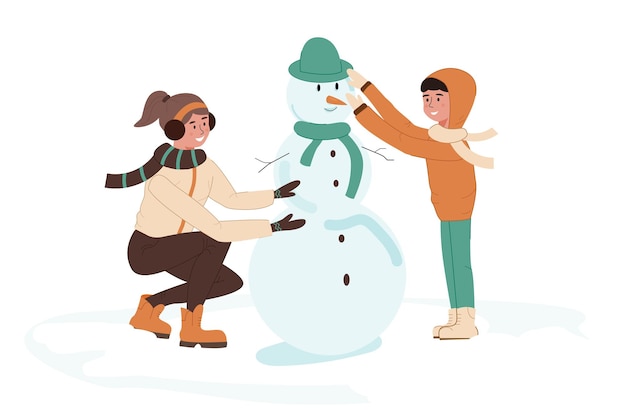 Children make a snowman out of snow A girl and a boy play outdoors during the winter holidays