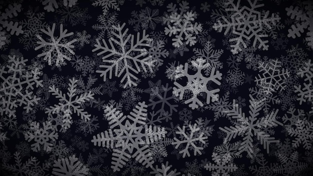 Christmas background of many layers of snowflakes of different shapes, sizes and transparency. White on black.