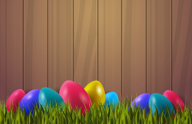 Vector colorful easter eggs on green grass over wooden textured background with copyspace