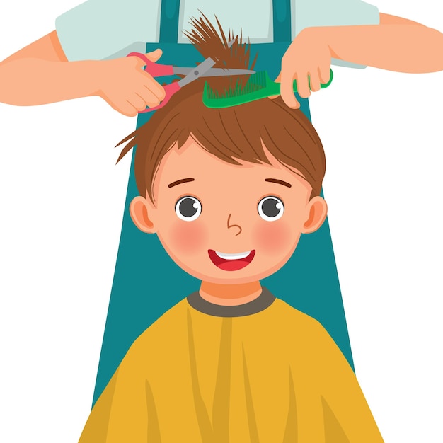 Cute little boy getting hair cut by hair dresser in the hair salon