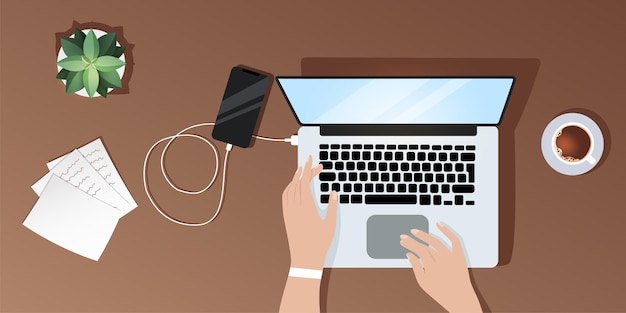 Desktop view from above, a girl works at a laptop, charges her phone, documents lie nearby coffee