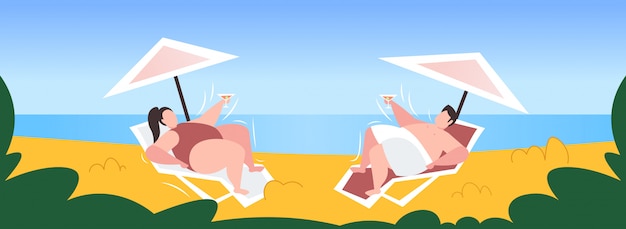 dikke zwaarlijvige man vrouw zonnen overgewicht paar cocktail drinken liggend op een ligstoel onder paraplu ongezonde levensstijl zwaarlijvigheid concept kust