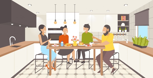 Famiglia seduta al tavolo da pranzo genitori e figli facendo colazione moderna cucina interna orizzontale a figura intera