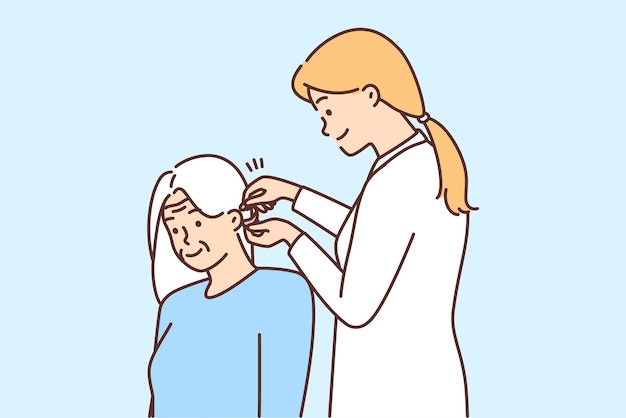 Женщина-врач устанавливает слуховой аппарат старому пациенту