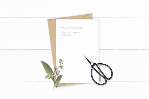 Flat lay top view elegant white composition letter kraft paper envelope flower leaf and vintage metal scissors on wooden background.