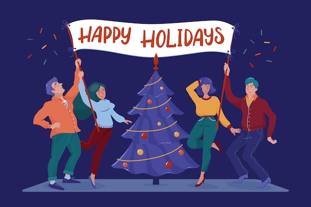 Four happy, smiling people, men and women, holding placard with happy holidays greeting text near christmas tree