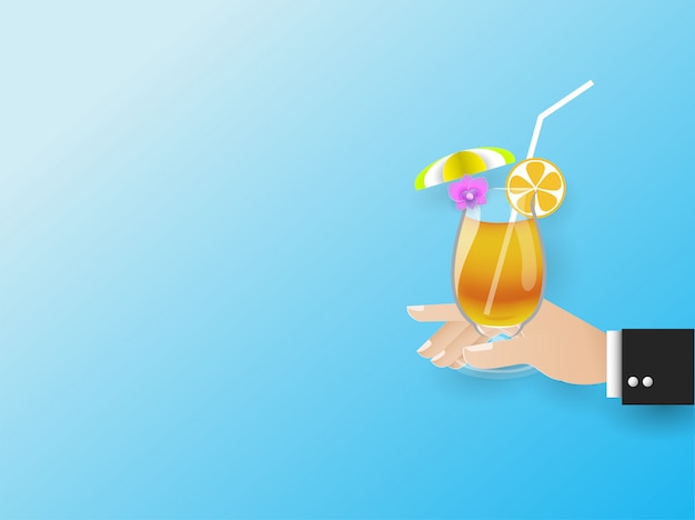 La mano dell'uomo d'affari in possesso di un bicchiere di succo d'arancia con un ombrello giallo e fiori sul vetro, estate