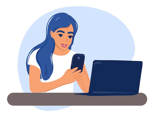 Счастливая деловая женщина сидит за столом с ноутбуком, держит в руках смартфон