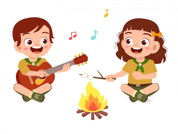 幸せなかわいいスカウトの男の子と女の子がキャンプファイヤーで歌う