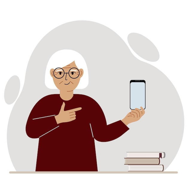 A happy grandmother holds a mobile phone in one hand and points at it with the index finger of his other hand.