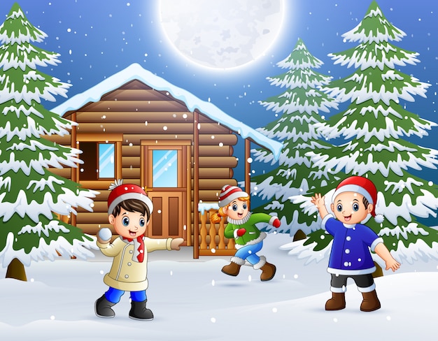 Happy kids play in front of a snowy wooden house