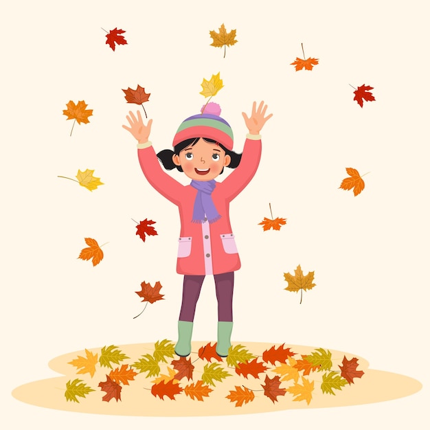 happy little girl playing outside with fallen leaves in autumn
