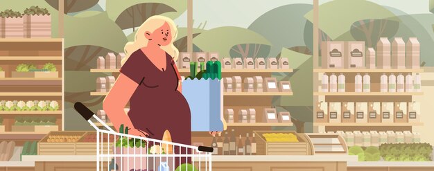 幸せな妊婦 ⁇ 将来のお母さん ⁇ 食料品のショッピングカートを押す ⁇ 妊娠 ⁇ 母性の期待 ⁇ コンセプト ⁇ 食料品店のインテリア