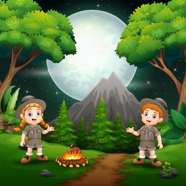 Happy scout boy and girl with a campfire at night