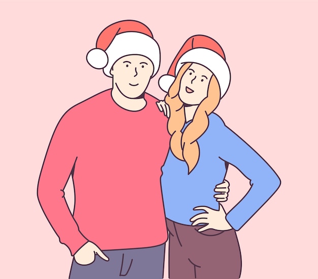 幸せな笑顔の若いカップルのクリスマスの帽子を抱いて