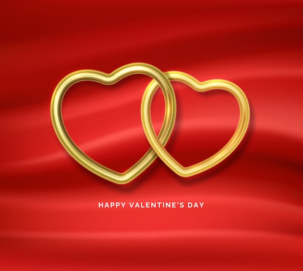 Buon san valentino. due forme a cuore d'oro collegate tra loro su tessuto di seta rosso.