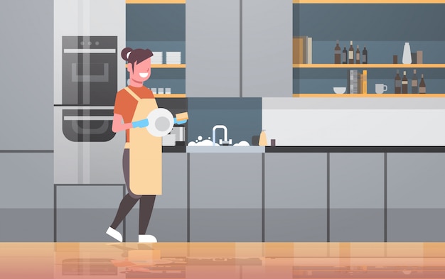 Jonge vrouw afwassen glimlachend meisje afvegen platen moderne keuken interieur afwassen concept huisvrouw huishoudelijk werk doen