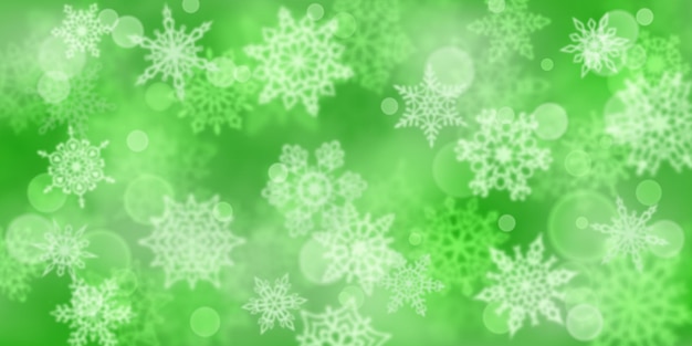 Kerstachtergrond van wazige sneeuwvlokken in groene kleuren