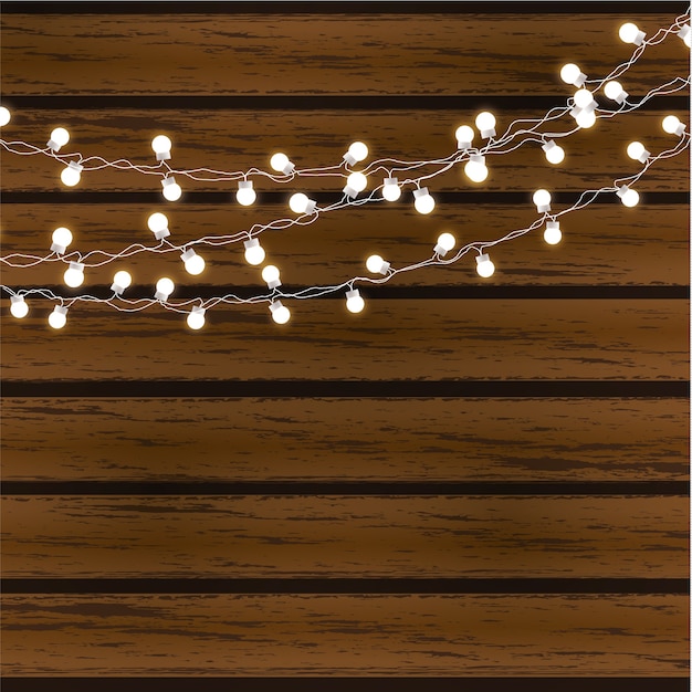 Kerstverlichting geïsoleerd op donkere houten achtergrond. glow garland gloeilampen op draden.