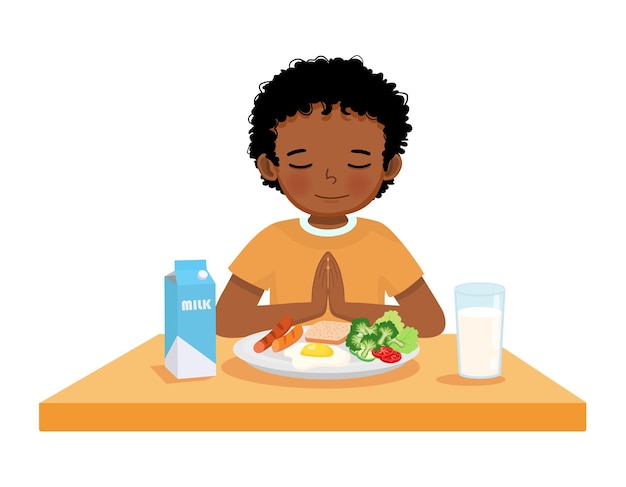 テーブルで朝食を食べる前に祈っているアフリカの小さな少年