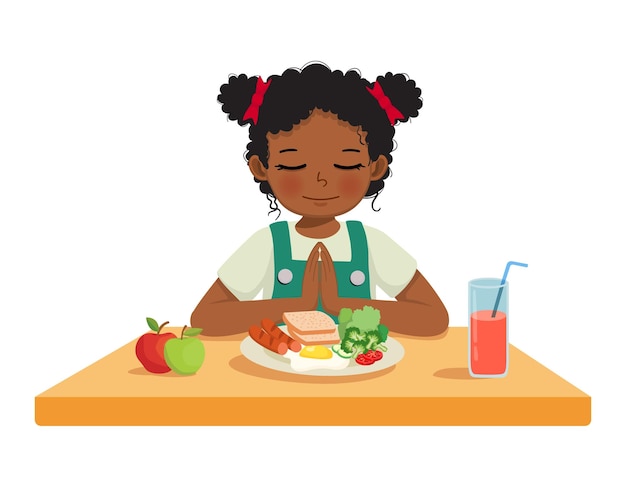 テーブルで朝食を食べる前に祈っている小さなアフリカの女の子