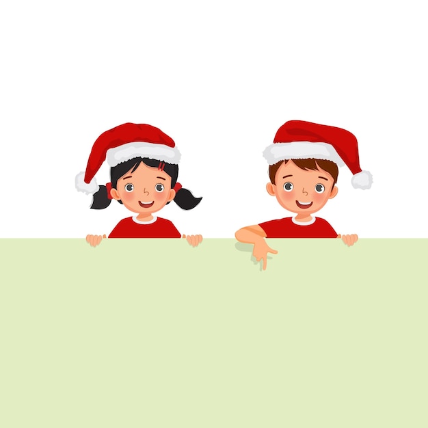 Little boy and girl in santa hat standing behind empty banner pointing finger over the board