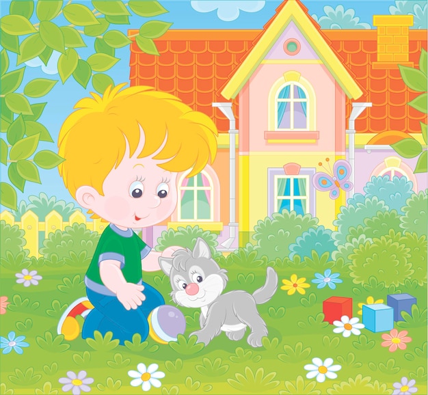 Little boy playing with a small grey kitten among flowers on green grass of a lawn