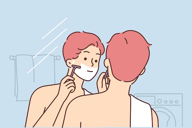 Мужчина бреет лицо, стоя в ванной и глядя в зеркало, выполняя ежедневную утреннюю гигиену