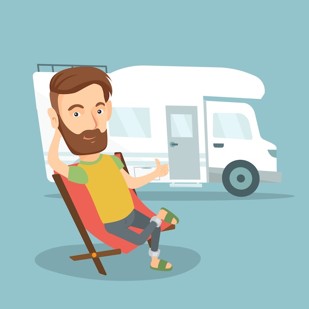 Man sitting in chair in front of camper van.