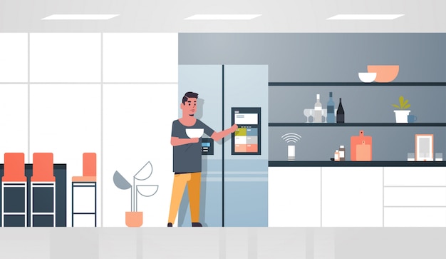 man touching refrigerator screen with smart speaker